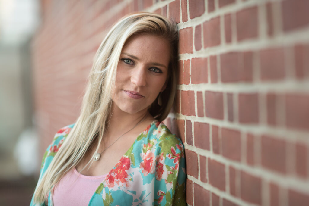 high school senior photography, girl leaning up against brick smiling